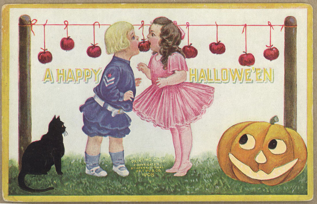 Vintage Halloween postcard of two white children biting the same apple on a string from a row of apples on strings, black cat and jack-o'-lantern in foreground